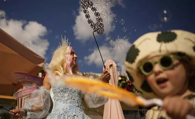 An actress blows bubbles on a beach of Pionersky pond at Gorky park in Moscow, Russia, Friday, Aug. 15, 2025. (AP Photo/Pavel Bednyakov)