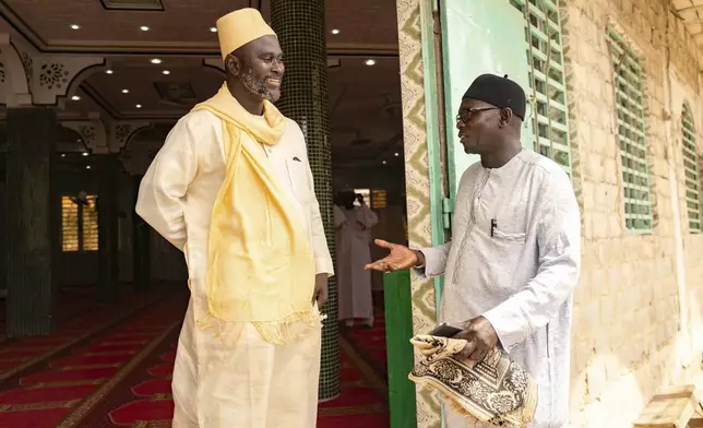 Imam Ibrahima Diane, left, advocate for an end to gender-based violence and practices like female genital mutilation, discusses with El Hadj Malick, coordinator of the "École des Maris" program at the Great Mosque of Nietty Mbar in Thiaroye, a suburb of Dakar, Senegal, Friday, July 4, 2025.(AP Photo/Sylvain Cherkaoui)