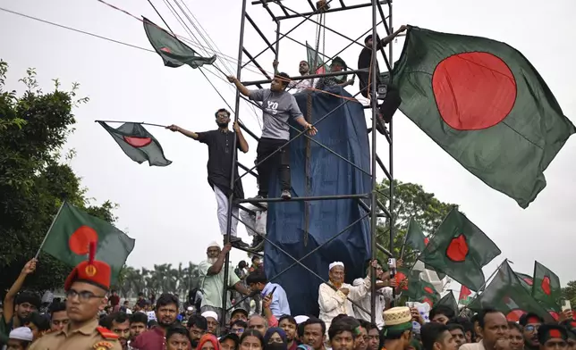 People wave national flags as they gather to commemorate "July Uprising Day" marking the anniversary of the fall of the Awami League government, in Dhaka, Bangladesh, Tuesday, Aug. 5, 2025. (AP Photo/Mahmud Hossain Opu)