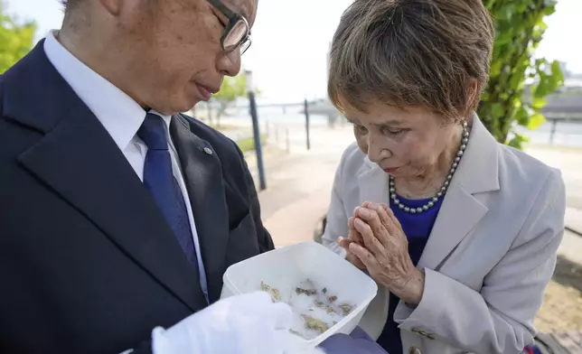 Tamiko Sora, right, 83, an atomic bombing survivor in Hiroshima, puts her hands together in prayer after being shown a fragment of human bone found on Ninoshima Island by Rebun Kayo, left, a Hiroshima University researcher, on Wednesday, July 9, 2025, in Hiroshima, western Japan. (AP Photo/Eugene Hoshiko)