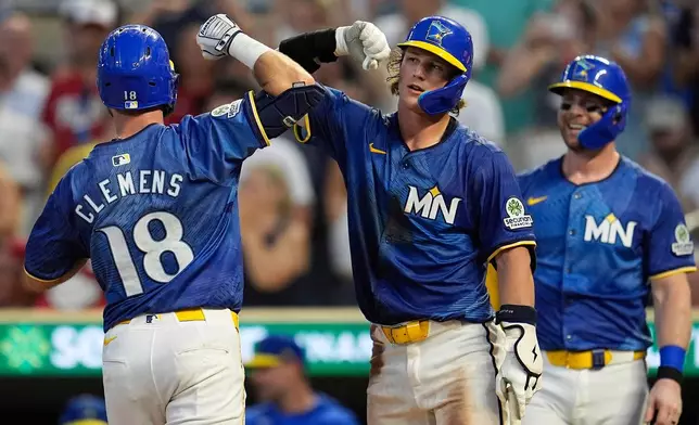 Minnesota Twins' Kody Clemens (18) celebrates with Luke Keaschall (15), center, after hitting a solo home run during the fourth inning of a baseball game against the Kansas City Royals, Friday, Aug. 8, 2025, in Minneapolis. (AP Photo/Abbie Parr)