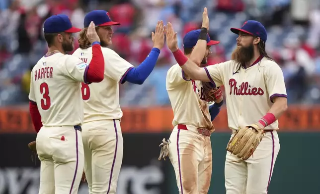 Philadelphia Phillies' Bryce Harper, from left, Alec Bohm, Trea Turner and Brandon Marsh celebrate after the Phillies won a baseball game against the Seattle Mariners Wednesday, Aug. 20, 2025, in Philadelphia. (AP Photo/Matt Slocum)
