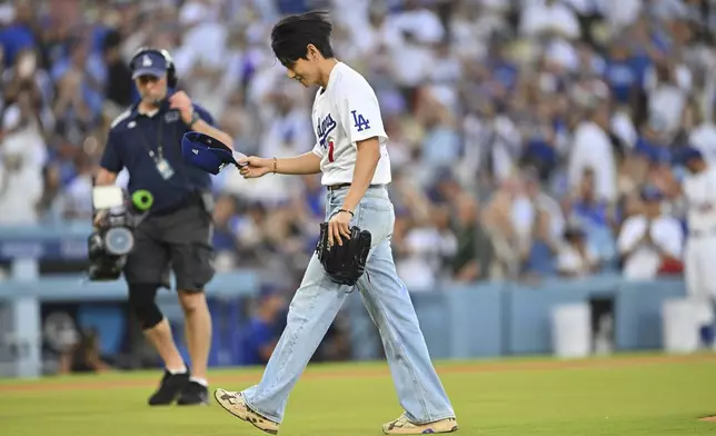 V, a member of the South Korean K-pop band BTS, takes off his cap after throwing out a ceremonial first pitch before a baseball game between the Los Angeles Dodgers and the Cincinnati Reds Monday, Aug. 25, 2025, in Los Angeles. (AP Photo/Jayne Kamin-Oncea)