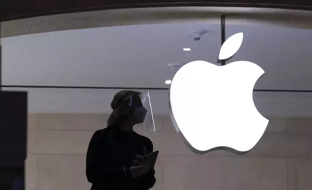 FILE - An Apple store employee stands inside the store in New York on Feb. 5, 2021. (AP Photo/Mark Lennihan, File )