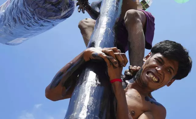 Participants compete in a greased-pole climbing competition held to celebrate Indonesia's 80th Independence Day, at Ancol Beach in Jakarta, Indonesia, Aug. 17, 2025. (AP Photo/Tatan Syuflana)