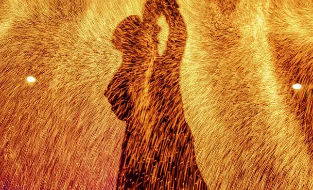 A pyrotechnician performs in the Fire Night Fountains show at the Palace of Versailles, outside Paris, Aug. 15, 2025. (AP Photo/Aurelien Morissard)