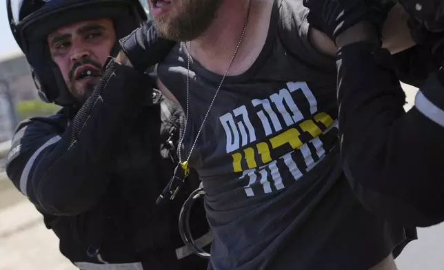 A demonstrator is detained for blocking a road with others during a protest demanding the immediate release of hostages held by Hamas and calling for the Israeli government to reverse its decision to take over Gaza City and other areas in the Gaza Strip, in Tel Aviv, Israel, Aug. 17, 2025. (AP Photo/Ohad Zwigenberg)