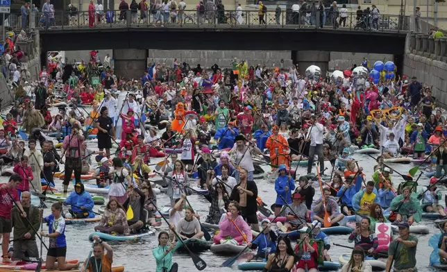 People steer their stand-up paddle (SUP) boards along the Kriukov Channel at the annual costumed 'Fontanka' SUP-boards festival attracting more than 10,000 participants, in St. Petersburg, Russia, Saturday, Aug. 2, 2025. (AP Photo/Dmitri Lovetsky)