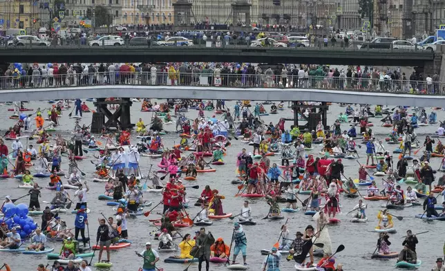 People steer their stand-up paddle (SUP) boards along Fontanka River during annual costumed 'Fontanka' SUP-boards festival attracted more than 10,000 participants, in St. Petersburg, Russia, Saturday, Aug. 2, 2025. (AP Photo/Dmitri Lovetsky)