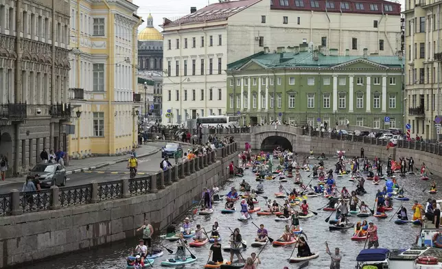 People steer their stand-up paddle (SUP) boards along the Moyka River at the annual costumed 'Fontanka' SUP-boards festival attracting more than 10,000 participants, in St. Petersburg, Russia, Saturday, Aug. 2, 2025. (AP Photo/Dmitri Lovetsky)