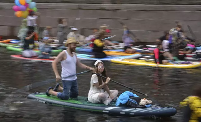 People steer their stand-up paddle (SUP) boards along the Kriukov Channel at the annual costumed 'Fontanka' SUP-boards festival attracting more than 10,000 participants, in St. Petersburg, Russia, Saturday, Aug. 2, 2025. (AP Photo/Dmitri Lovetsky)