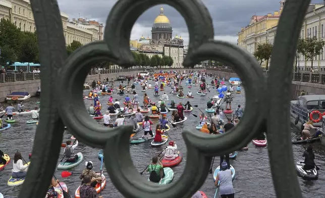 People steer their stand-up paddle (SUP) boards along the Moyka River at the annual costumed 'Fontanka' SUP-boards festival attracting more than 10,000 participants, in St. Petersburg, Russia, Saturday, Aug. 2, 2025. (AP Photo/Dmitri Lovetsky)