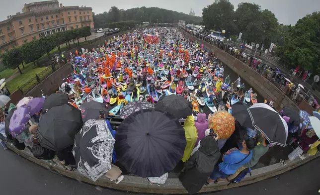 People steer their stand-up paddle (SUP) boards during rainfall along the Moyka River at the annual costumed 'Fontanka' SUP-boards festival attracting more than 10,000 participants, in St. Petersburg, Russia, Saturday, Aug. 2, 2025. (AP Photo/Dmitri Lovetsky)