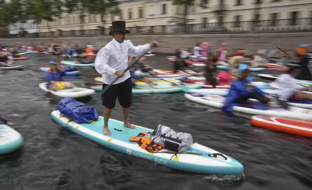 People steer their stand-up paddle (SUP) boards along the Kriukov Channel at the annual costumed 'Fontanka' SUP-boards festival attracting more than 10,000 participants, in St. Petersburg, Russia, Saturday, Aug. 2, 2025. (AP Photo/Dmitri Lovetsky)