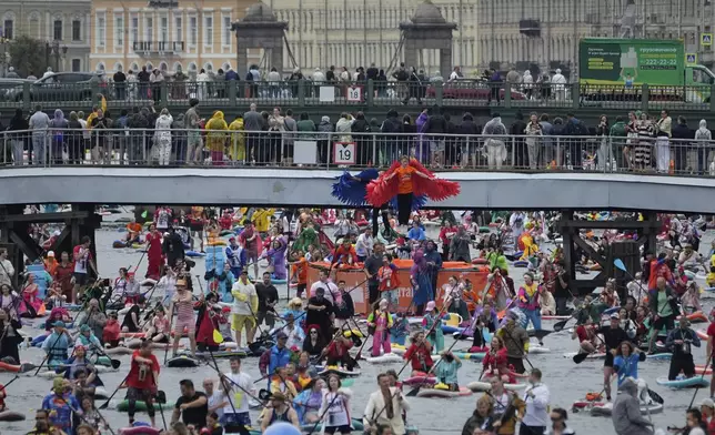 People steer their stand-up paddle (SUP) boards along the Moyka River at the annual costumed 'Fontanka' SUP-boards festival attracting more than 10,000 participants, in St. Petersburg, Russia, Saturday, Aug. 2, 2025. (AP Photo/Dmitri Lovetsky)