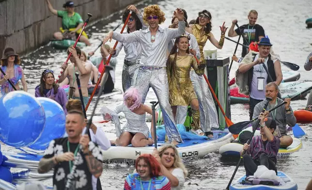People steer their stand-up paddle (SUP) boards along the Moyka River at the annual costumed 'Fontanka' SUP-boards festival attracting more than 10,000 participants, in St. Petersburg, Russia, Saturday, Aug. 2, 2025. (AP Photo/Dmitri Lovetsky)