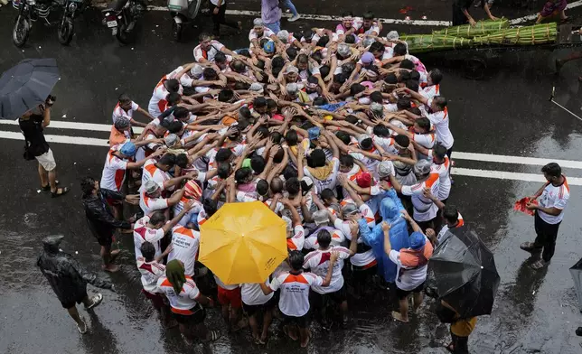 Devotees try to form a human pyramid to break a clay pot containing curd hanging above during the celebrations to mark the Hindu festival of Janmashtami in Mumbai, India, Saturday, Aug. 16, 2025. (AP Photo/Rajanish Kakade)