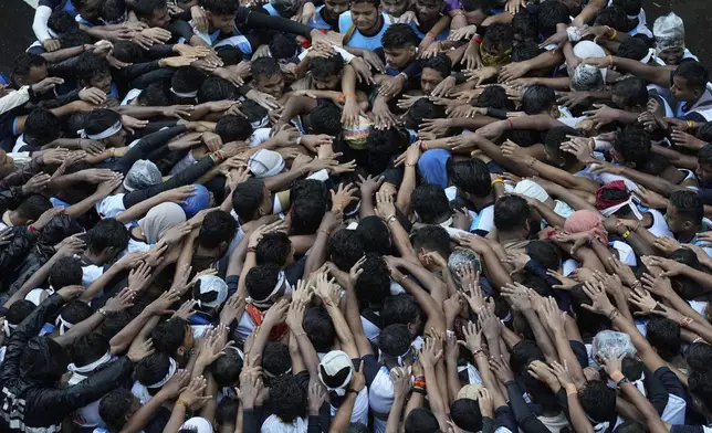 Devotees try to form a human pyramid to break a clay pot containing curd hanging above during the celebrations to mark the Hindu festival of Janmashtami in Mumbai, India, Saturday, Aug. 16, 2025. (AP Photo/Rajanish Kakade)