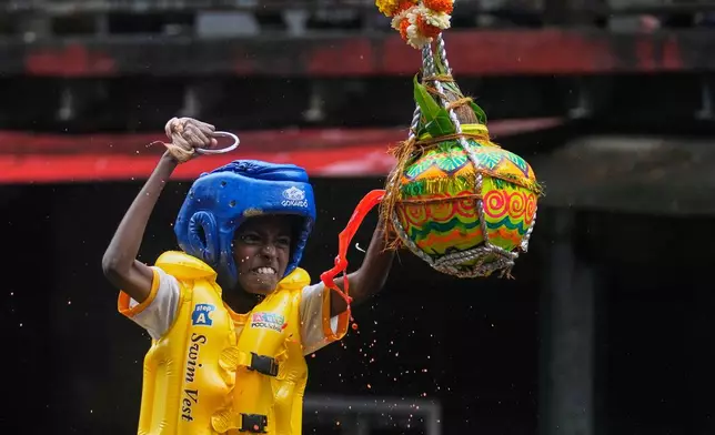 Curd spills as a boy tries to break an earthen pot filled with curd, after climbing on top of a human pyramid as part of celebrations to mark Janmashtami festival in Mumbai, India, Saturday, Aug. 16, 2025. (AP Photo/Rajanish Kakade)