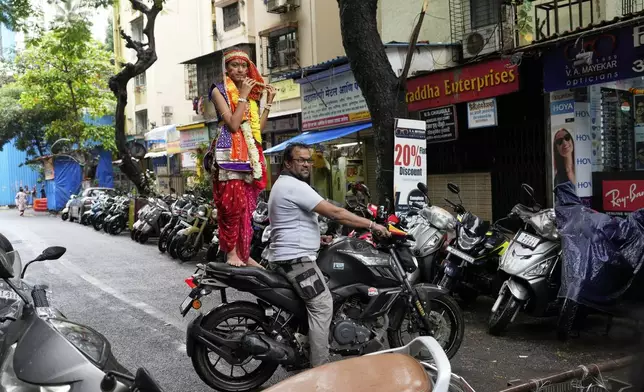 A girl dressed as Hindu deity Lord Krishna stands on a motorcycle during celebrations to mark Janmashtami festival in Mumbai, India, Saturday, Aug. 16, 2025. (AP Photo/Rajanish Kakade)
