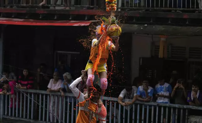Curd spills as Indian devotees form a human pyramid and break an earthen pot filled with curd, as part of celebrations to mark Janmashtami festival in Mumbai, India, Saturday, Aug. 16, 2025. (AP Photo/Rajanish Kakade)