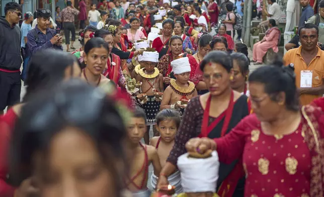 Devotees light oil lamps on their hands, heads, and shoulders during a parade celebrating the birthday of Lord Krishna on Krishna Janmashtami in Bhaktapur,Nepal, Saturday, Aug. 16, 2025. (AP Photo/Niranjan Shrestha)