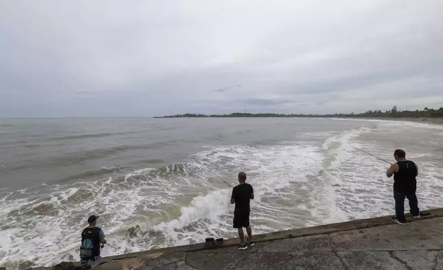 People fish along the shore in Arecibo, Puerto Rico, as Hurricane Erin brings rains to the island, Sunday, Aug. 17, 2025. (AP Photo/Alejandro Granadillo)