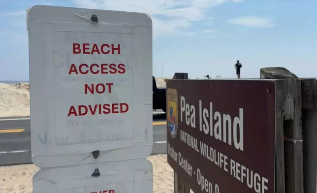 In this image taken from video provided by WVEC-TV, a sign warning against beach access is posted in Dare County, N.C., Monday, Aug. 18, 2025, ahead of expected impacts from Hurricane Erin. (WVEC-TV via AP)