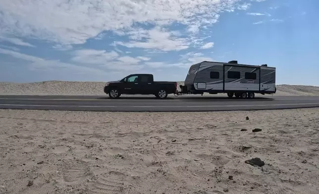 In this image taken from video provided by WVEC-TV, a vehicle with a trailer is traveling on Highway 12 in Dare County, N.C., Monday, Aug. 18, 2025, ahead of expected impacts from Hurricane Erin. (WVEC-TV via AP)