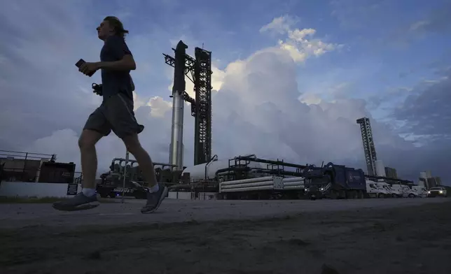 A jogger passes as SpaceX's mega rocket Starship is prepared for a test flight from Starbase, Texas, Tuesday, Aug. 26, 2025. (AP Photo/Eric Gay)