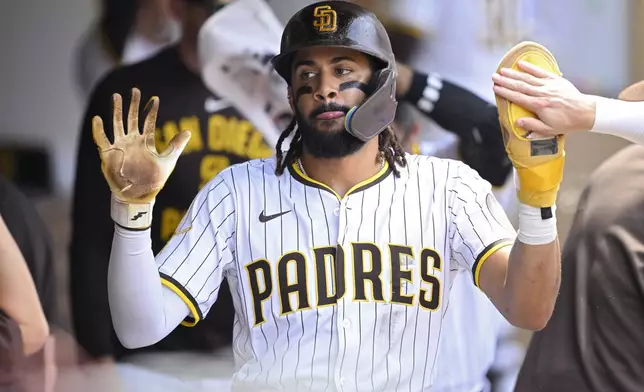 San Diego Padres' Fernando Tatis Jr. is congratulated in the dugout after scoring on a single by Manny Machado during the fourth inning of a baseball game against the San Francisco Giants, Thursday, Aug. 21, 2025, in San Diego. (AP Photo/Orlando Ramirez)
