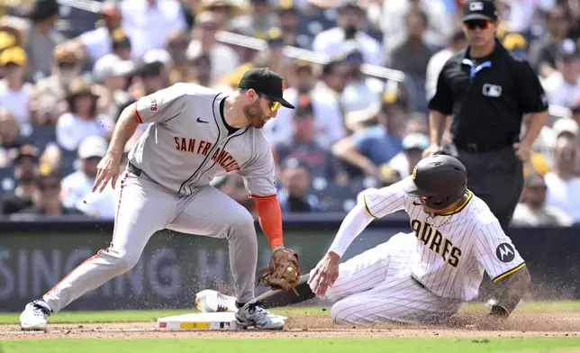 San Diego Padres' Manny Machado, front right, steals third base ahead of a tag by San Francisco Giants third baseman Casey Schmitt, left, during the fifth inning of a baseball game Thursday, Aug. 21, 2025, in San Diego. (AP Photo/Orlando Ramirez)