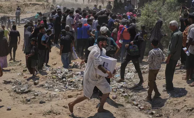 Palestinians rush to collect humanitarian aid airdropped by parachutes into Zawaida in the central Gaza Strip, Monday, Aug. 4, 2025. (AP Photo/Abdel Kareem Hana)