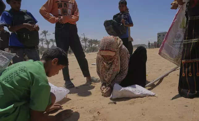 Palestinians collect lentils from the ground after humanitarian aid was airdropped by parachutes into Zawaida, in the central Gaza Strip, Monday, Aug. 4, 2025. (AP Photo/Abdel Kareem Hana)