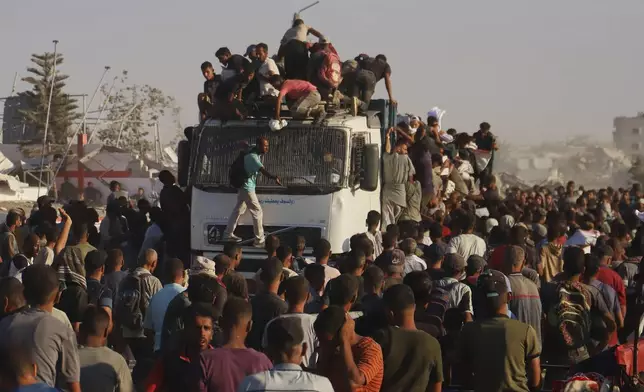 Palestinians ride on a truck loaded with food and humanitarian aid as it moves along the Morag corridor near Rafah, in the southern Gaza Strip, Monday, Aug. 4, 2025. (AP Photo/Mariam Dagga)