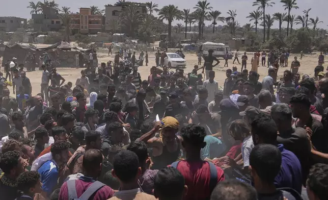 A man holds up a knife as Palestinians rush to collect humanitarian aid airdropped by parachutes into Zawaida, in the central Gaza Strip, Monday, Aug. 4, 2025. (AP Photo/Abdel Kareem Hana)