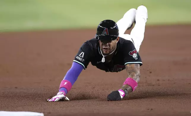 Arizona Diamondbacks' Ketel Marte slides safely into third base after a hit by Geraldo Perdomo against the Colorado Rockies during the first inning of a baseball game Saturday, Aug. 9, 2025, in Phoenix. (AP Photo/Chris Coduto)