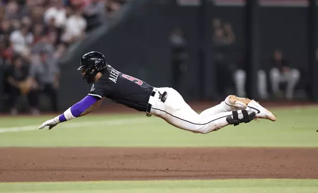 Arizona Diamondbacks' Blaze Alexander slides safely into third base after hitting a single and advancing on a throwing error by Colorado Rockies starting pitcher Bradley Blalock during the fourth inning of a baseball game Saturday, Aug. 9, 2025, in Phoenix. (AP Photo/Chris Coduto)