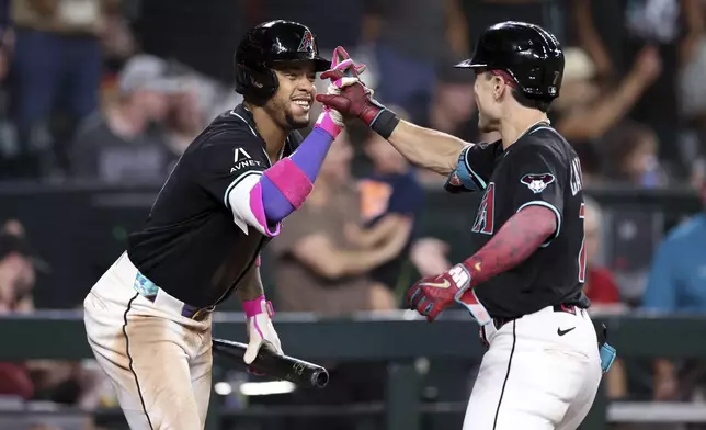 Arizona Diamondbacks' Corbin Carroll, right, high-fives Ketel Marte, left, after hitting a two-run home run against the Colorado Rockies during the fifth inning of a baseball game Saturday, Aug. 9, 2025, in Phoenix. (AP Photo/Chris Coduto)