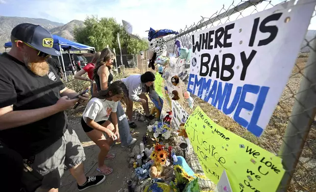 Visitors gather around a makeshift memorial prior to a vigil for missing 7-month-old Emmanuel Haro outside the child's home in Cabazon, Calif. on Friday, Aug. 22, 2025. (Will Lester/The Orange County Register via AP)