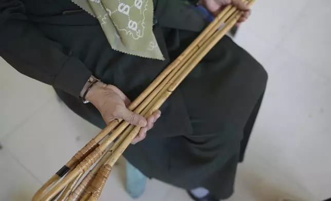 An official holds rattan sticks which will be used to cane people who violate Shariah law including two men convicted of hugging and kissing, which the court ruled can lead to banned sexual relations, in Banda Aceh, Aceh province, Indonesia, Tuesday, Aug. 26, 2025. (AP Photo/ Reza Saifullah)