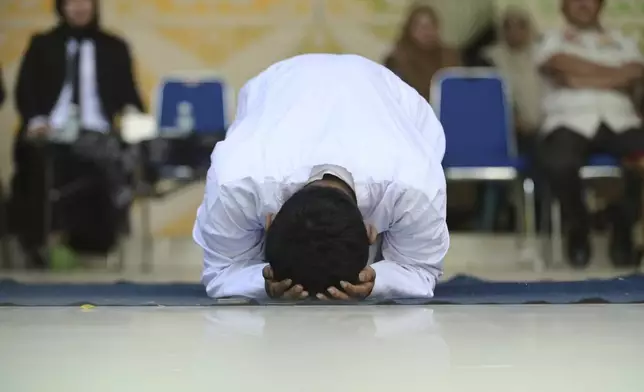 One of two men convicted of violating Islamic law by hugging and kissing, which the court ruled can lead to banned sexual relations, reacts after being caned in Banda Aceh, Aceh province, Indonesia, Tuesday, Aug. 26, 2025. (AP Photo/Reza Saifullah)