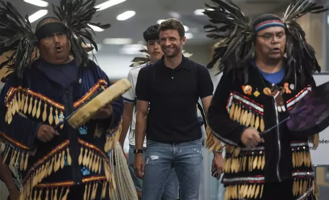 New Vancouver Whitecaps player Thomas Muller walks with members of the Musqueam First Nation as they drum and sing, after arriving from Germany at Vancouver International Airport in Richmond, British Columbia, Wednesday, Aug. 13, 2025. (Darryl Dyck/The Canadian Press via AP)