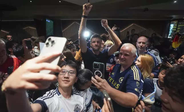 New Vancouver Whitecaps player Thomas Muller, center, dances as fans sing after arriving from Germany at Vancouver International Airport in Richmond, British Columbia, Wednesday, Aug. 13, 2025. (Darryl Dyck/The Canadian Press via AP)