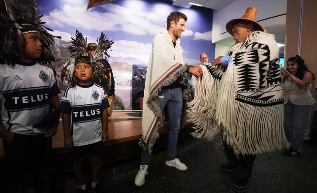 New Vancouver Whitecaps player Thomas Muller is greeted by Musqueam Chief Wayne Sparrow, right, as he arrives from Germany at Vancouver International Airport in Richmond, British Columbia, Wednesday, Aug. 13, 2025. (Darryl Dyck/The Canadian Press via AP)