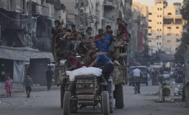 Palestinians ride on a truck carrying humanitarian aid collected from the northern Gaza Strip, as it moves along a street in Gaza City, Friday, Aug. 29, 2025. (AP Photo/Jehad Alshrafi)