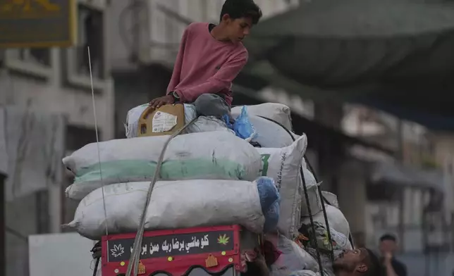 Displaced Palestinians fleeing Jabaliya move with their belongings on a street in Gaza City, Tuesday, Aug. 26, 2025. (AP Photo/Jehad Alshrafi)