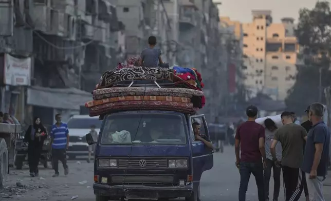 Displaced Palestinians fleeing northern Gaza Strip move with their belongings on a street in Gaza City, Friday, Aug. 29, 2025. (AP Photo/Jehad Alshrafi)