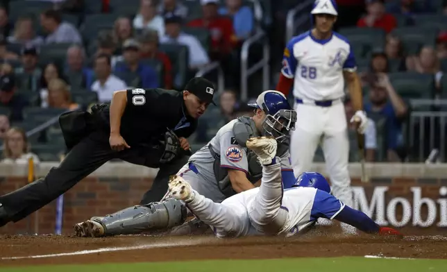 Atlanta Braves' Nacho Alvarez Jr. (67) is tagged out by New York Mets catcher Hayden Senger (30) as he slides into home plate during the third inning of a baseball game, Saturday, Aug. 23, 2025, in Atlanta. (AP Photo/Butch Dill)