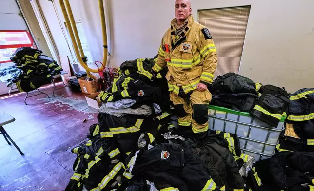 Firefighter Christopher Harrington stands next to the station's old turnout gear, while wearing recently issued non-PFAS turnout gear, at Fire Station 4 on July 3, 2025, in East Providence, R.I. (AP Photo/Charles Krupa)